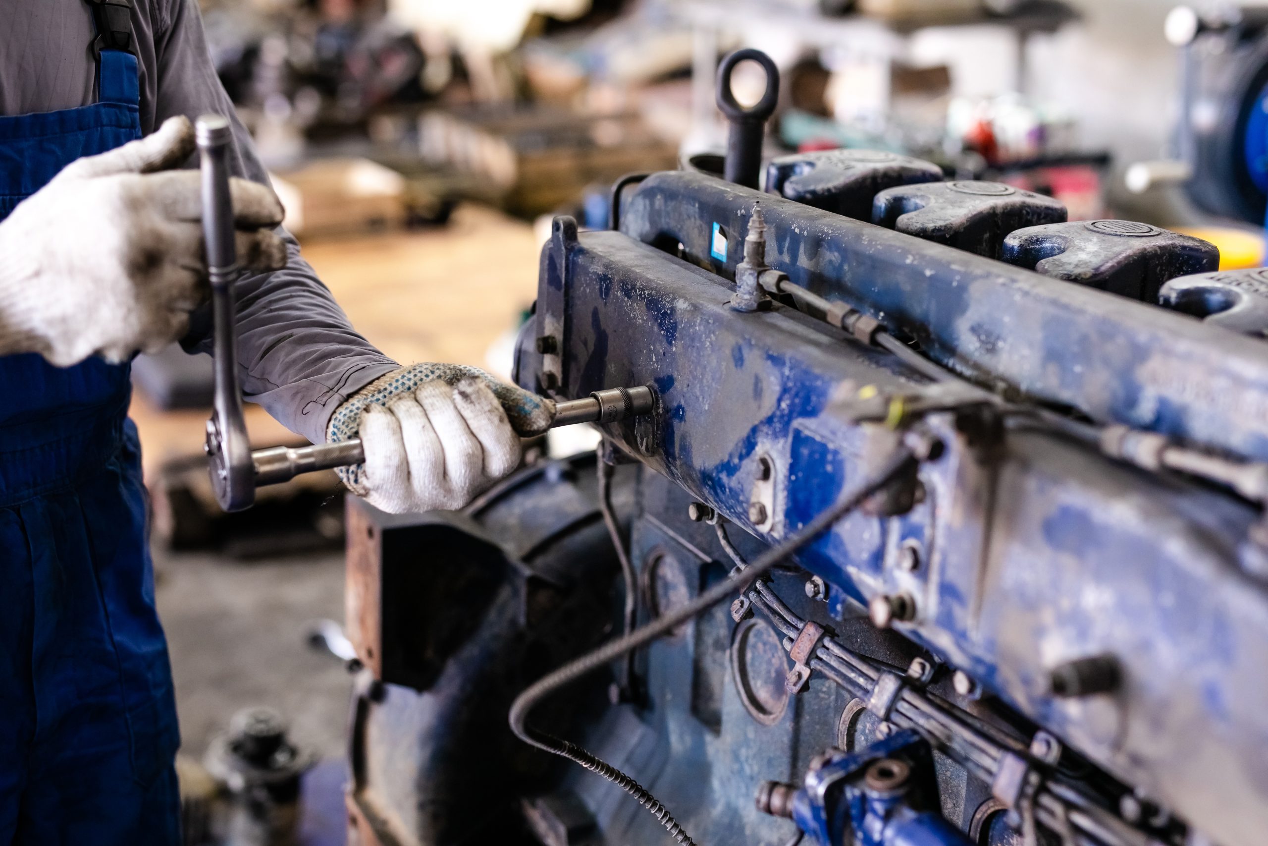 Mechanic repairs old motor of truck in a car repair station. Disassemble engine block vehicle. Motor capital repair. Car service concept.